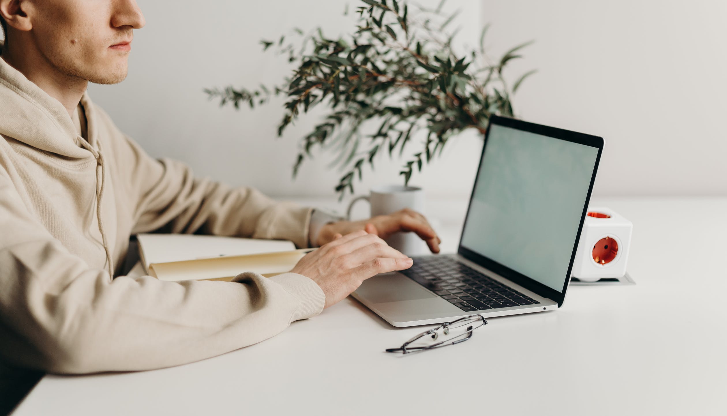 man typing next to a plant