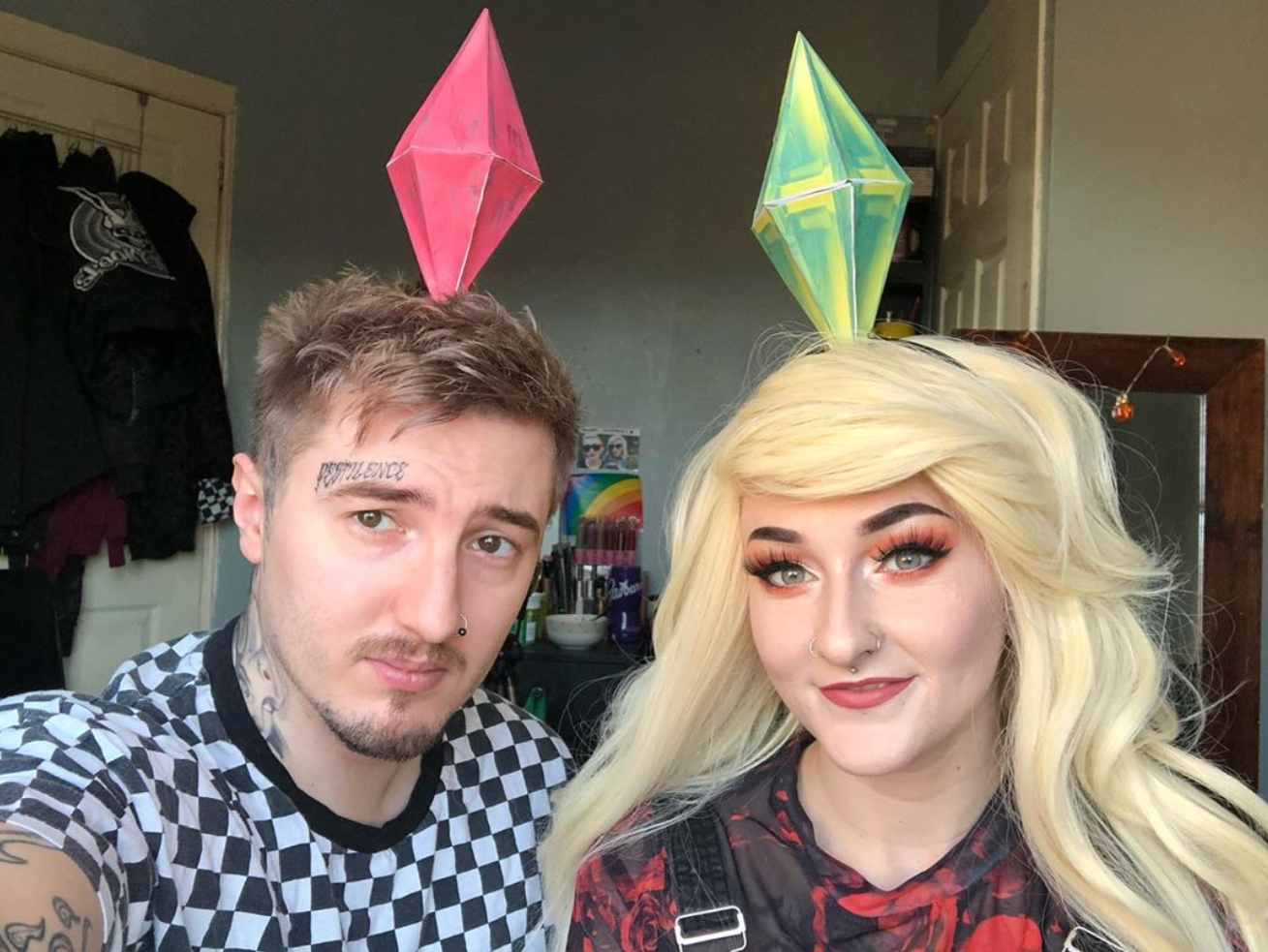 A couple poses with Sims headbands for their Sims costume.