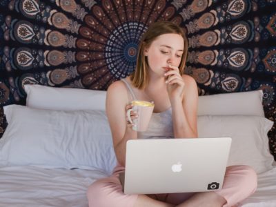 women on her computer with a tapestry and coffee