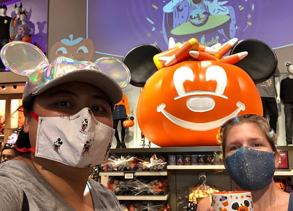 Two women pose in front of Downtown Disney merchandise in OC.