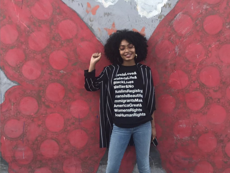 yara shahidi posing in front of a butterfly with an equal rights shirt