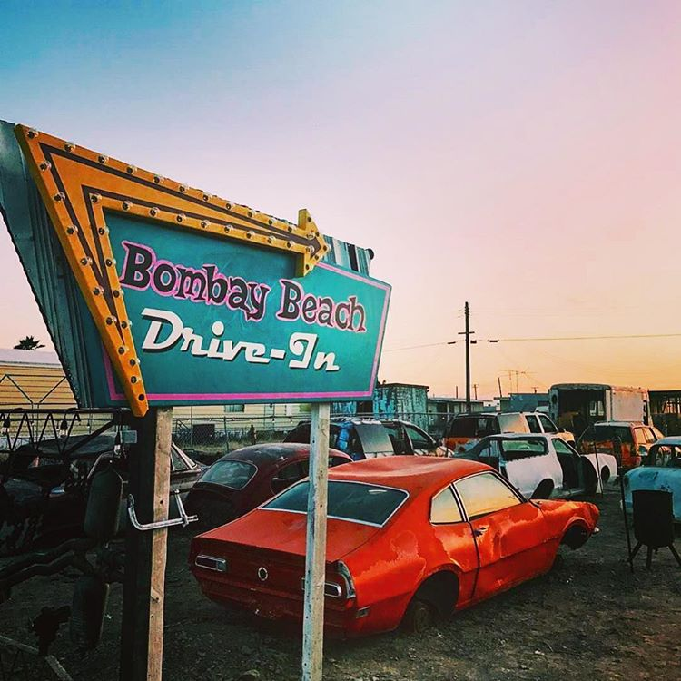 Bombay Beach decaying drive-in with rusted cars at sunset