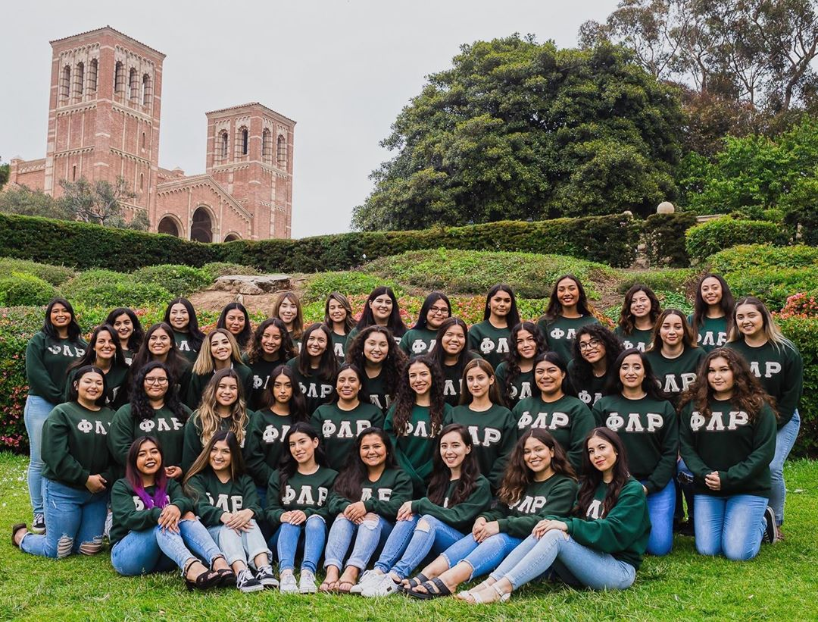 Latinas of Phi Lambda Rho posing in their green shirts on the grass outside of Powel Library.