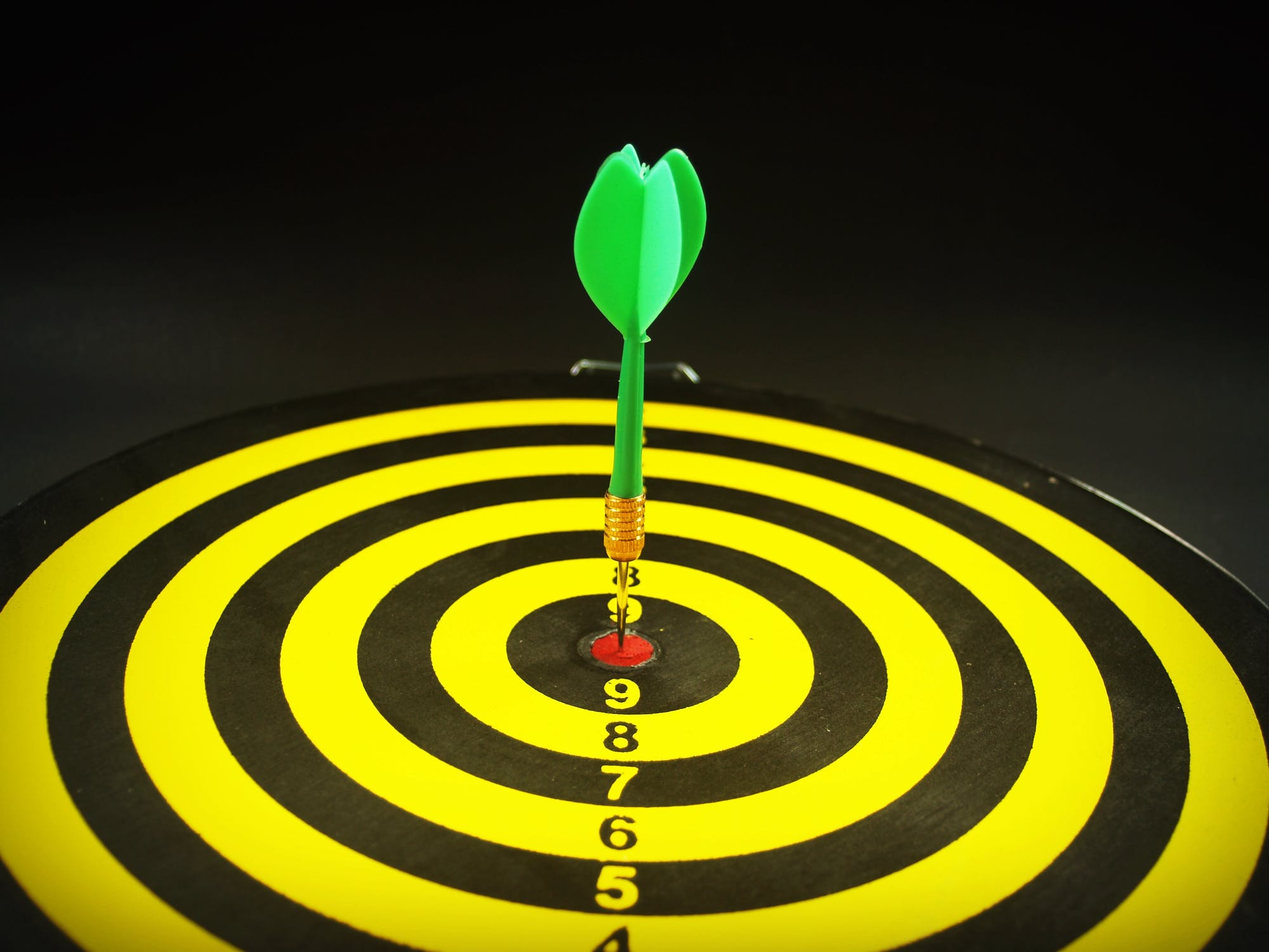 A dart sitting in the center of a target.