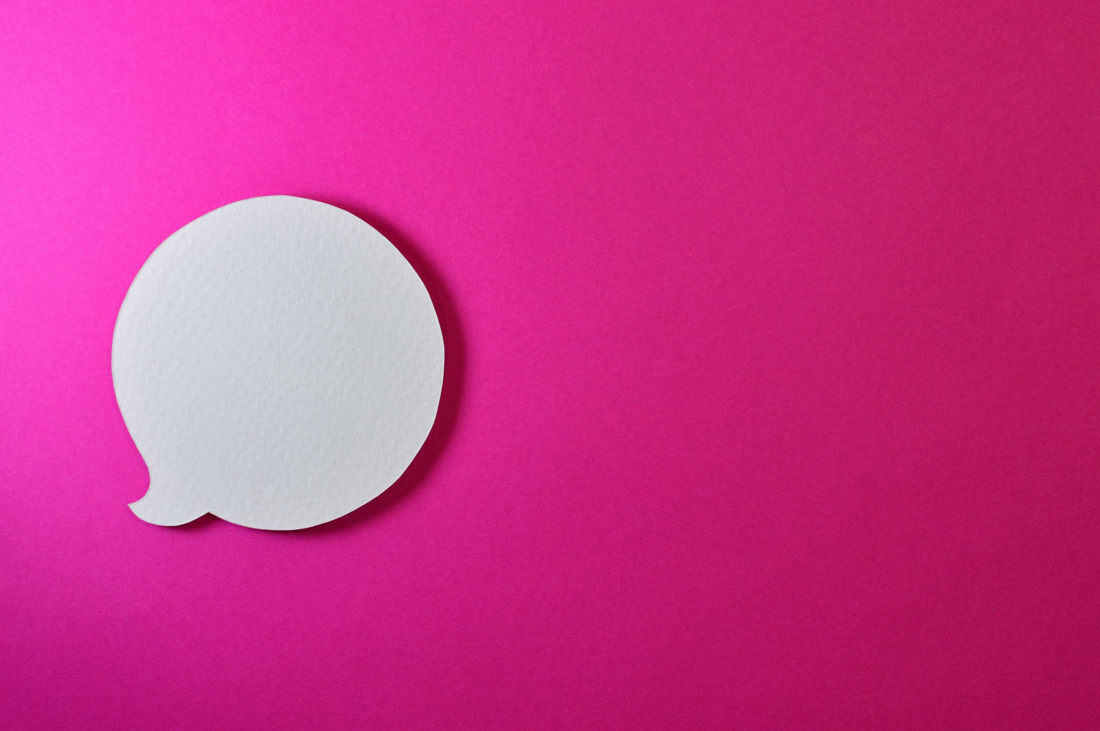 A paper speech bubble against a pink background because communication is an important part of office ethics.