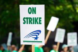 "On Strike" in green letters on a protestor's poster.
