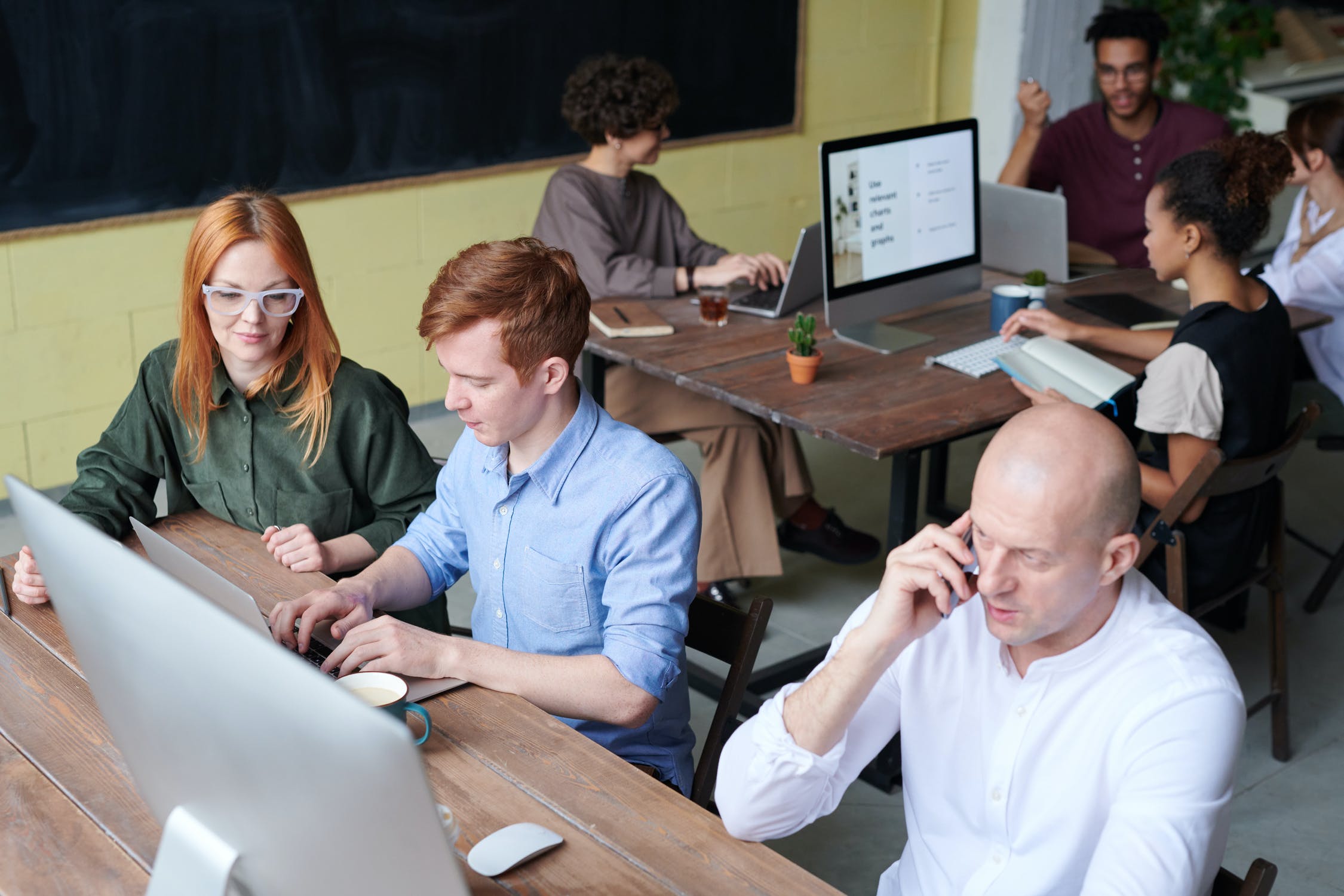 Three people sit at a desk.