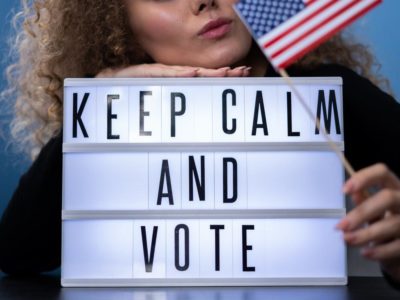 woman holding an American flag and a sign that says keep calm and vote