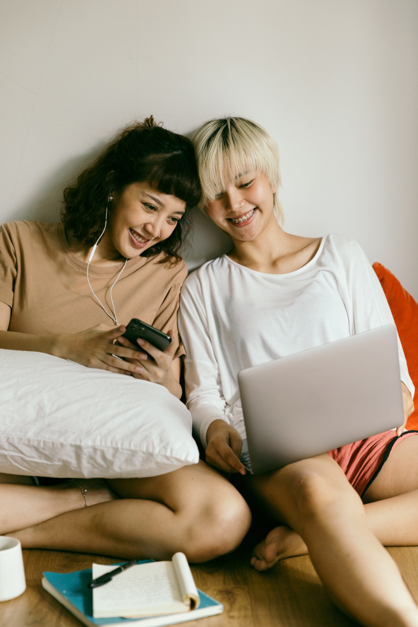 two friends watching media on their bed 