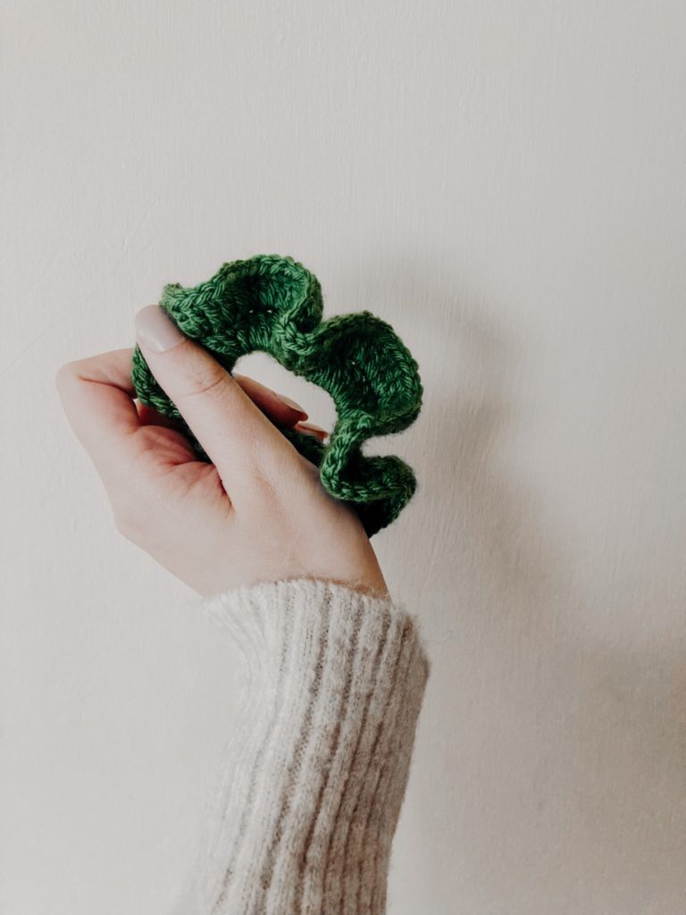 A hand holding a green scrunchie.