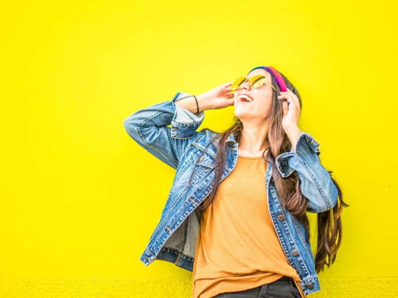 woman smiling in sunglasses yellow background