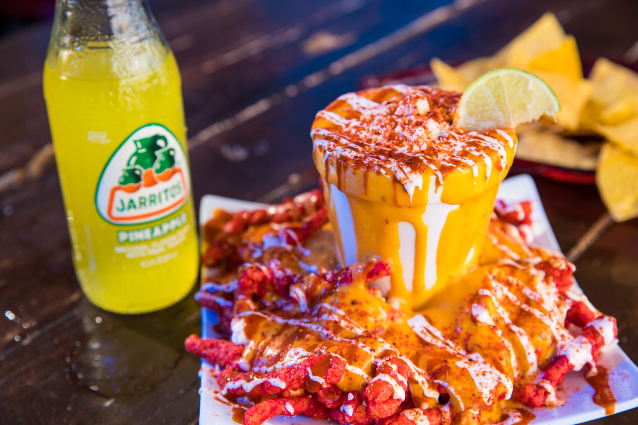 Yellow and green Jarritos bottle next to Mexican cuisine.