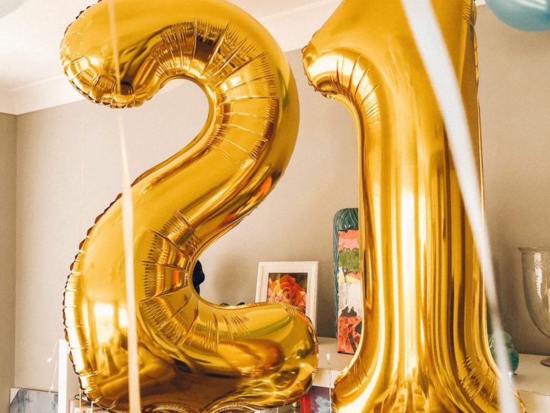 Brass-colored 21 foil balloons inside a room.