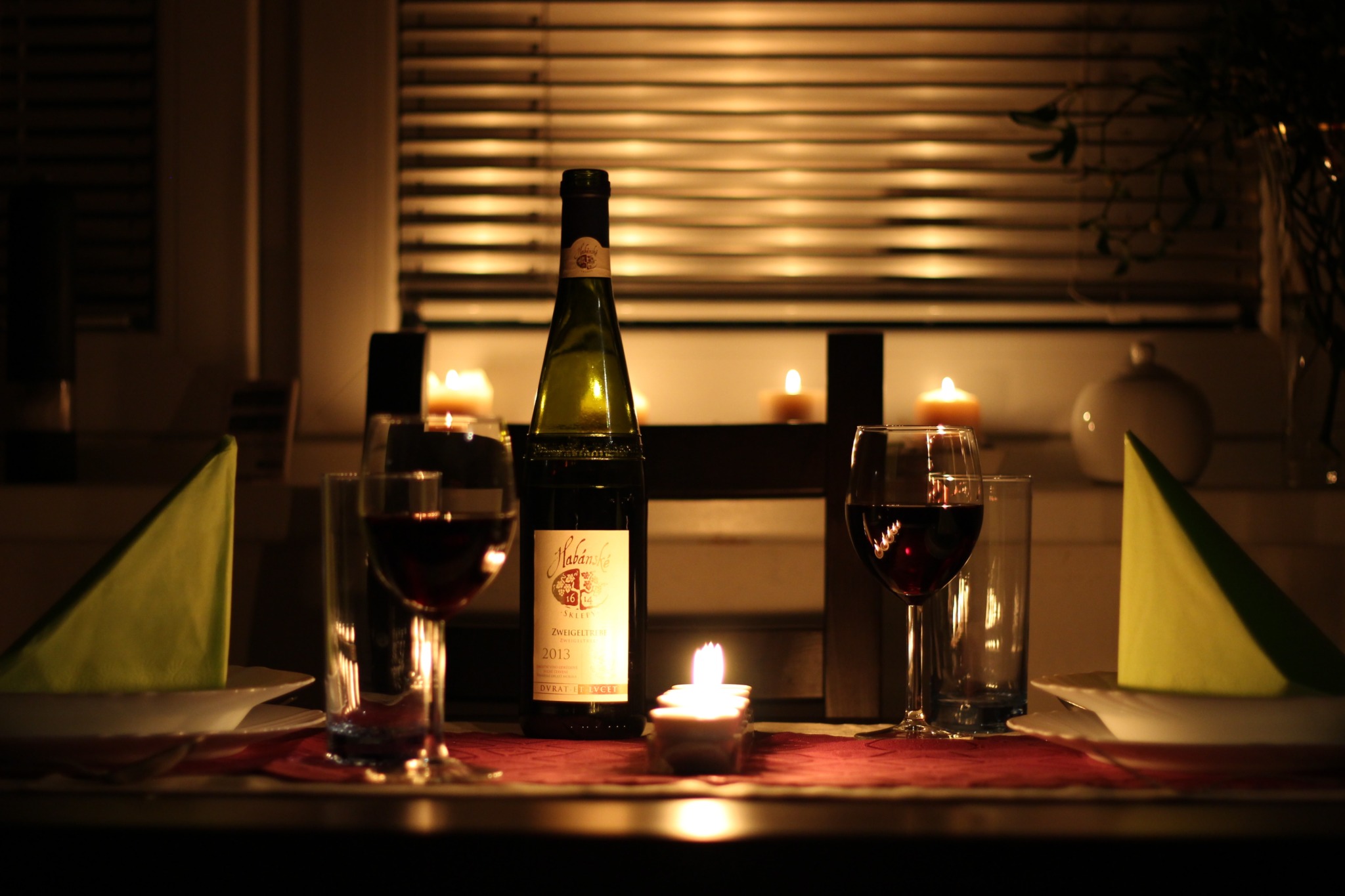 Two wine glasses filled with wine beside the original bottle.