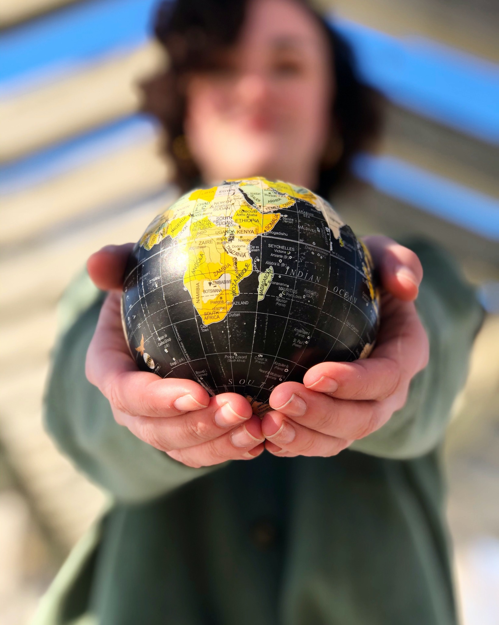 out of focus person holding an in-focus globe