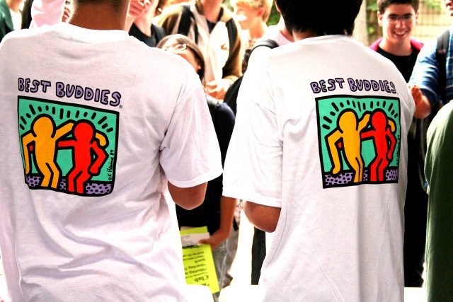 two people standing away from the camera wearing best buddies t-shirts 