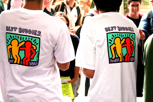 two people standing away from the camera wearing best buddies t-shirts