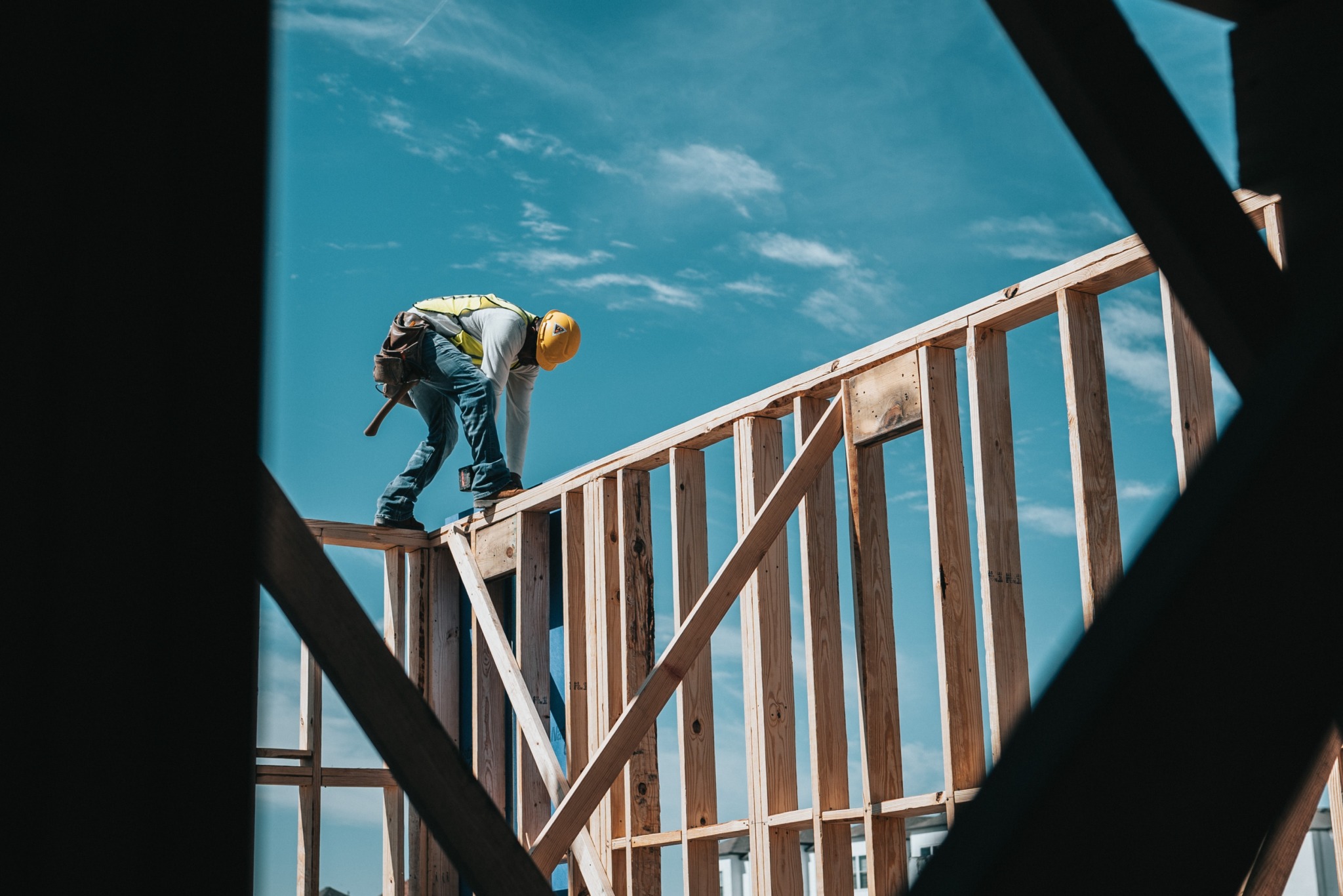 man in yellow shirt and blue denim building a house