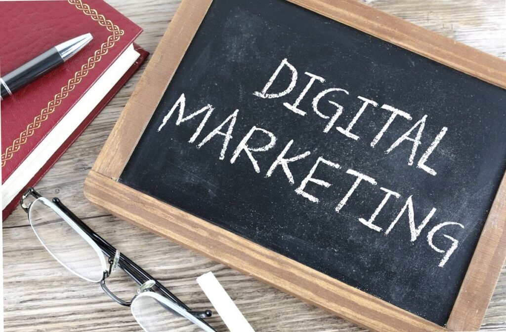 A chalkboard saying Digital Marketing with a notebook and pen
