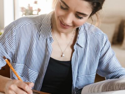 A girl sitting at a wooden table writing notes on the liberal arts major