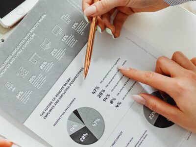 Hands holding a pencil and going over a sheet with a pie chart on it for a business major.