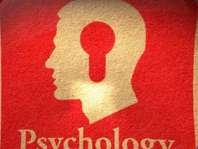 The word psychology and a human head on a red background with a magnifying glass around it