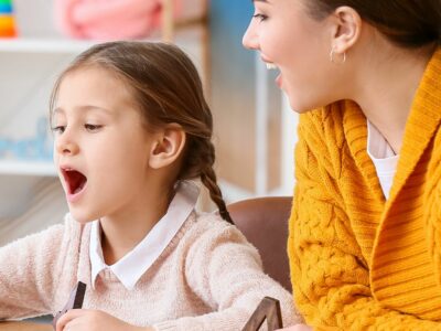 A speech pathologist teaching a little girl how to properly annunciate a word