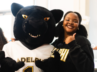 Girl at Adelphi posing with school mascot