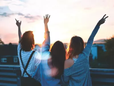 three girls staring at the sun and throwing peace signs